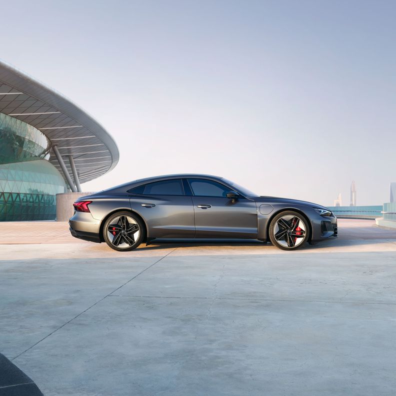 Audi RS e-tron GT sports car on a concrete surface in front of futuristic architecture.